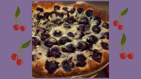 a golden brown dark cherry clafloutis on purple background
