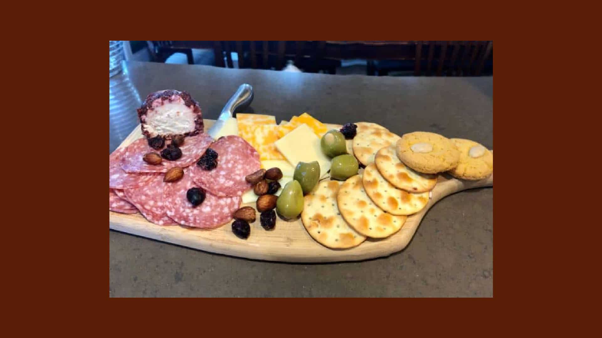 Cheese, meat, crackers, olives and fruit on a wooden board