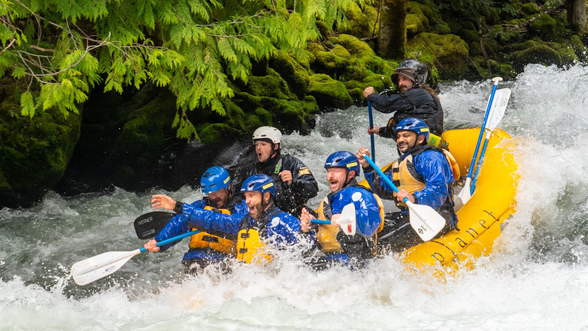 a yellow raft full of excited people going down a rapid