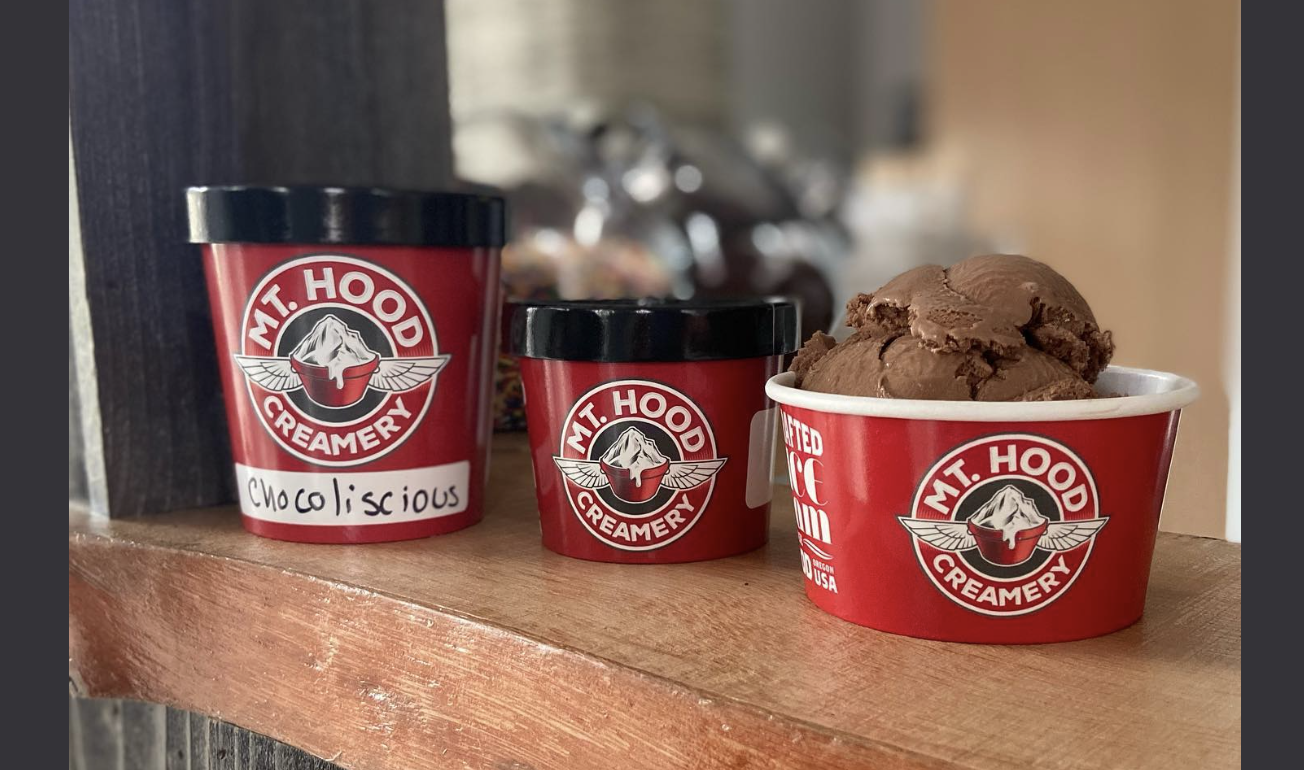 Three red containers of Mt. Hood Creamery ice cream on a wooden shelf