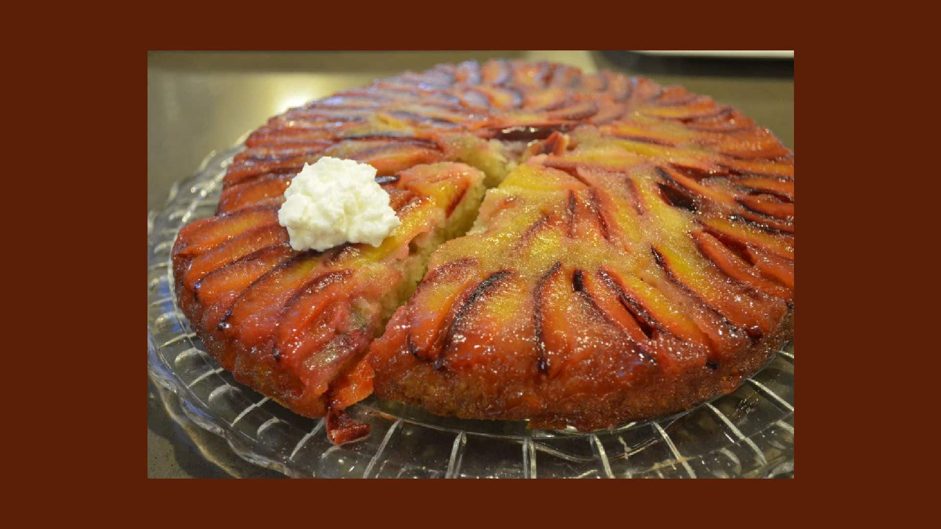 A plum upside down cake served on a round glass plate