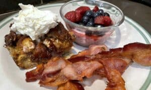 Blueberry Croissant French toast with bacon and a fruit dish 