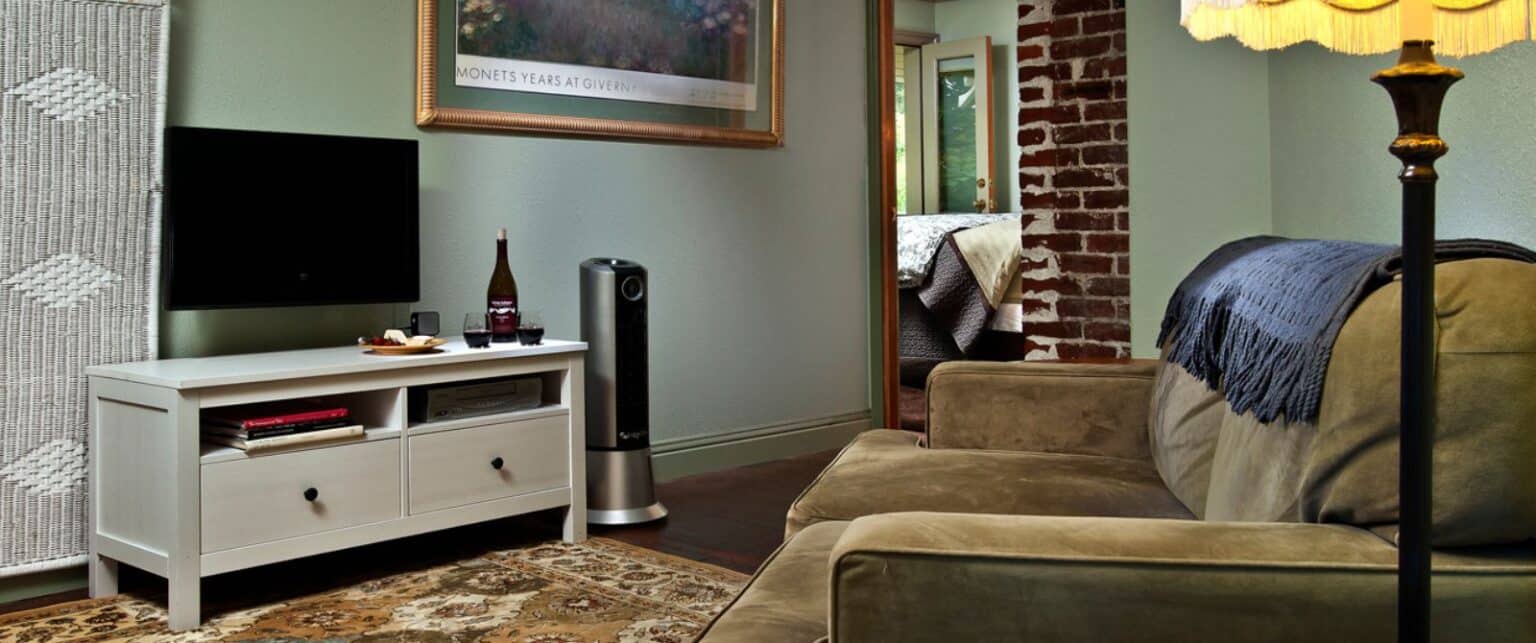A sitting area with a sofa, TV, and cabinet in a room with exposed brick and a rug.