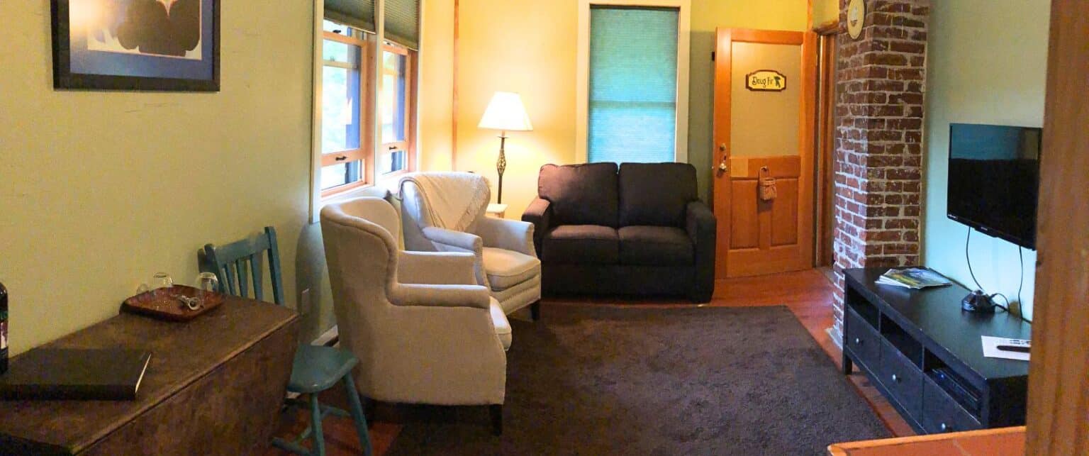 A wide view of a hotel room's living area with a TV, sitting area, and desk.