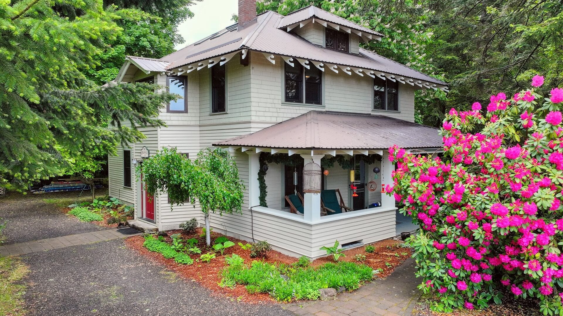Exterior image of the Old Parkdale Inn B&B behind a bright red rhododendron bush