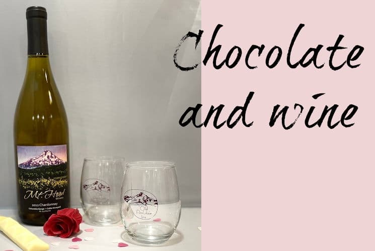 bottle of wine with 2 wine glasses, chocolate and rose petals
